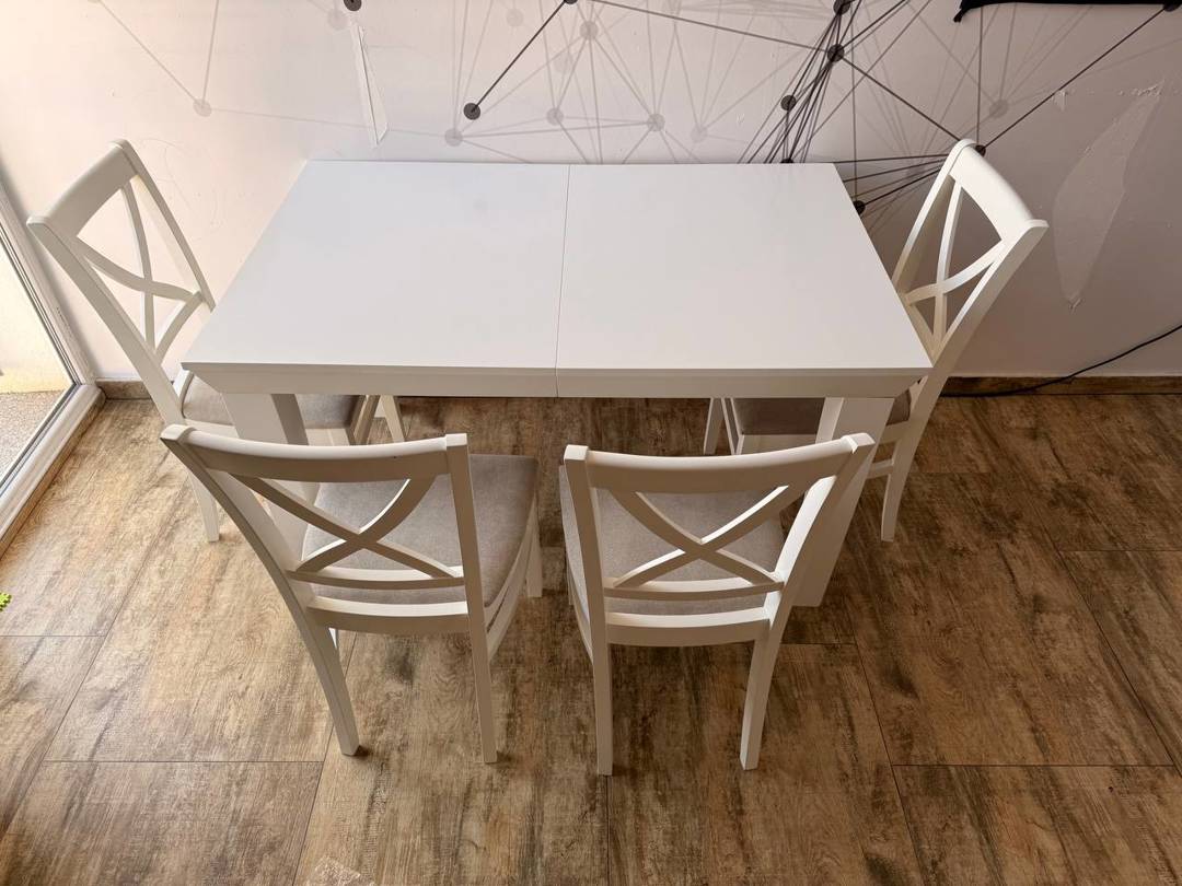 Dining table with extendable top and 4 white chairs.